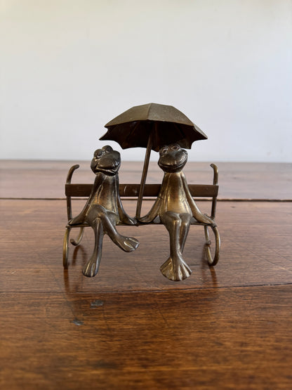 Vintage Brass Frogs Sitting on Bench Under Umbrella