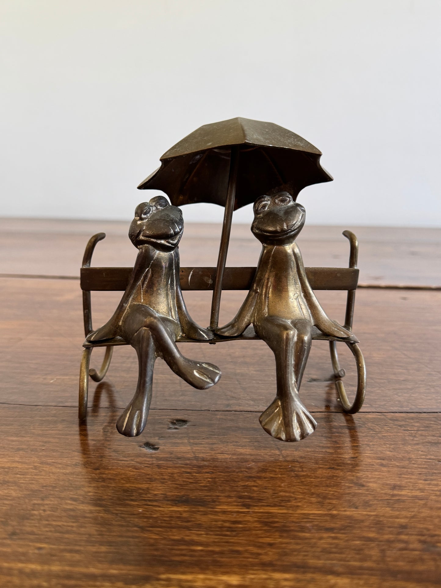 Vintage Brass Frogs Sitting on Bench Under Umbrella