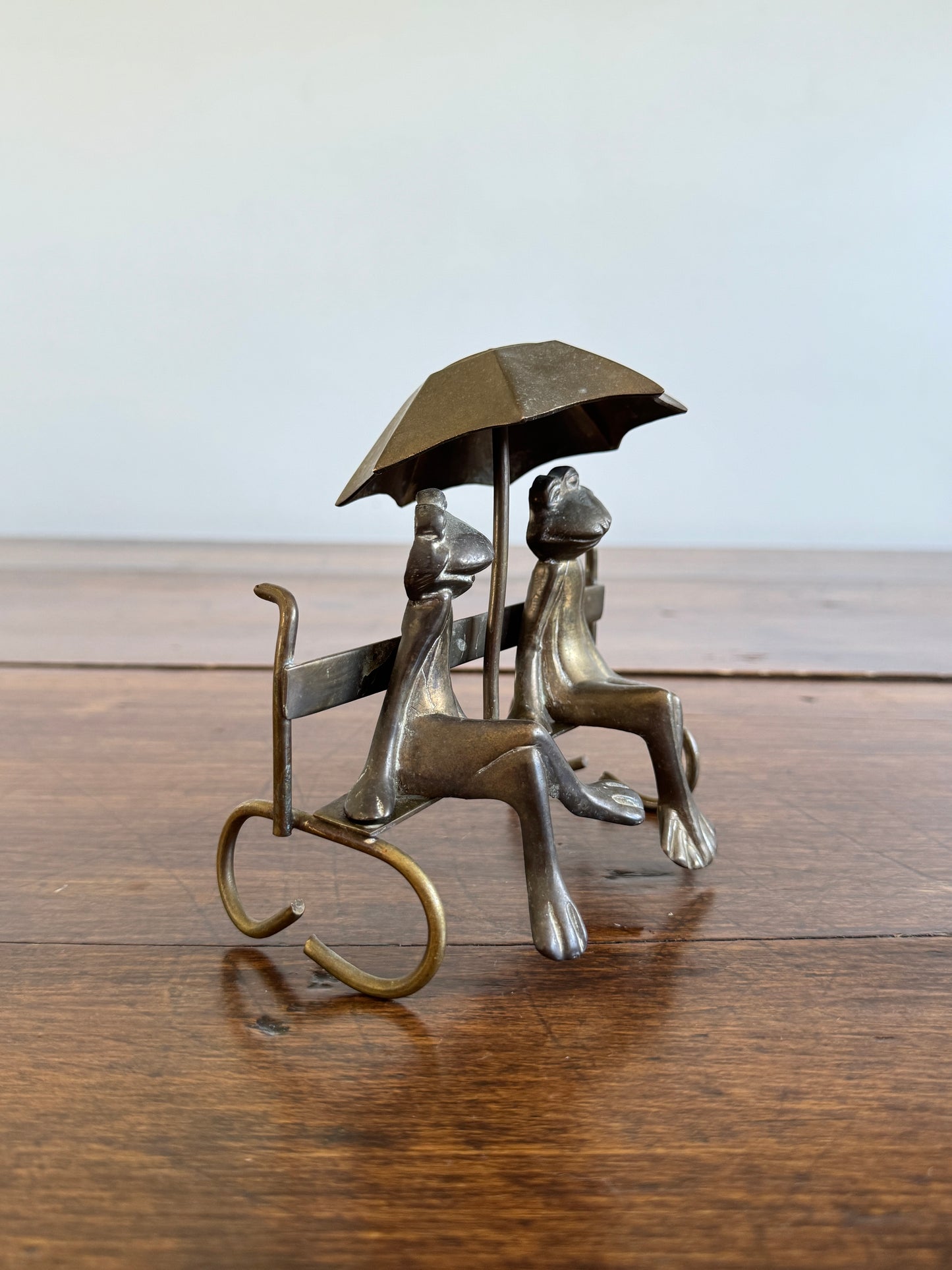 Vintage Brass Frogs Sitting on Bench Under Umbrella